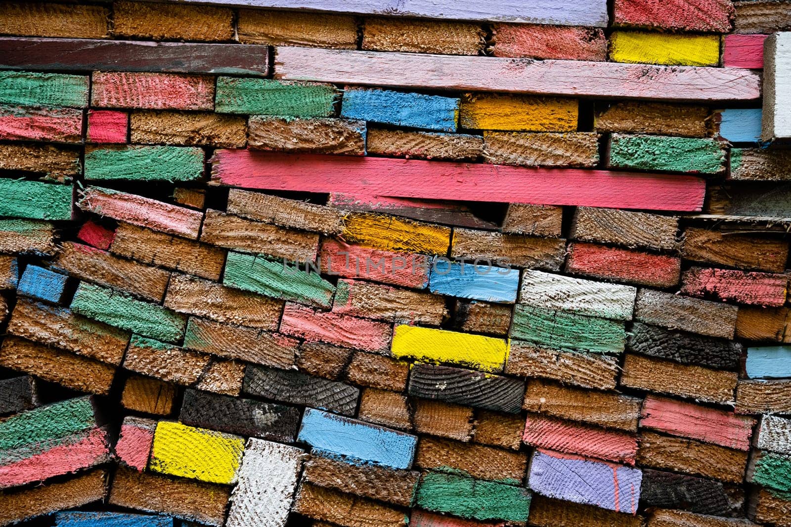 closeup front view of stacked wooden planks decorated with paint in different colors