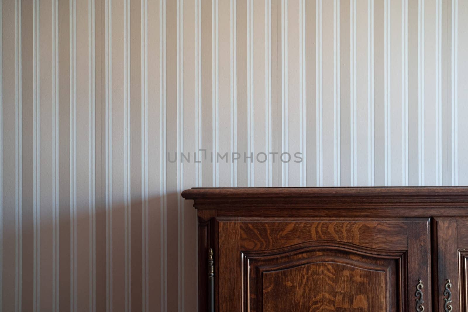front view close up of empty brown vintage drawer wooden cabinet against a white wall with beige stripes