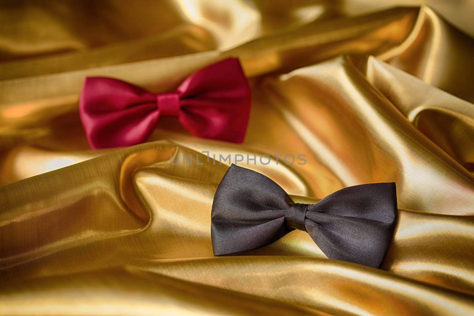 Red and black bow ties on draped golden satin
