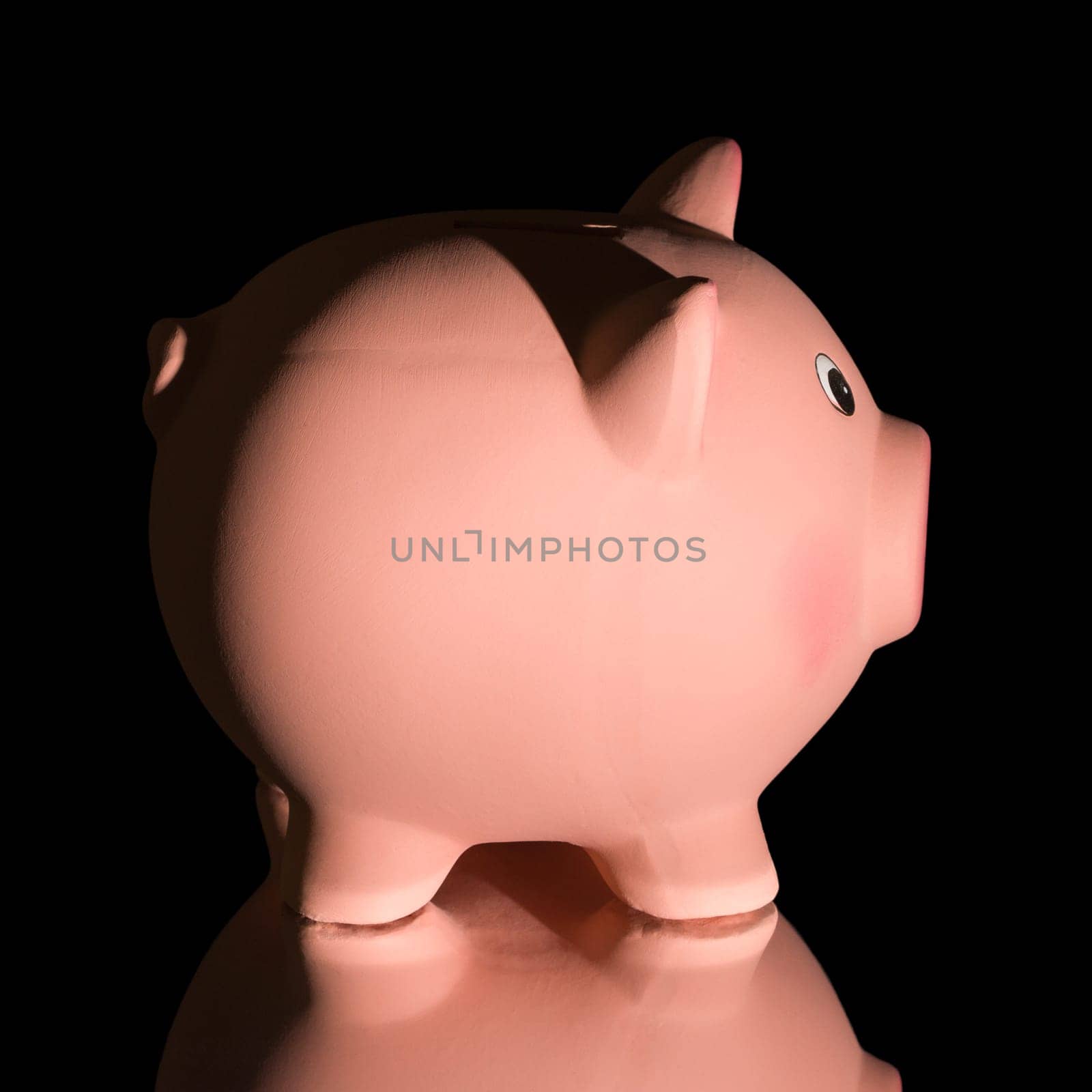 Pink ceramic piggy bank, on black background. Bank savings, economy, financials investments concept