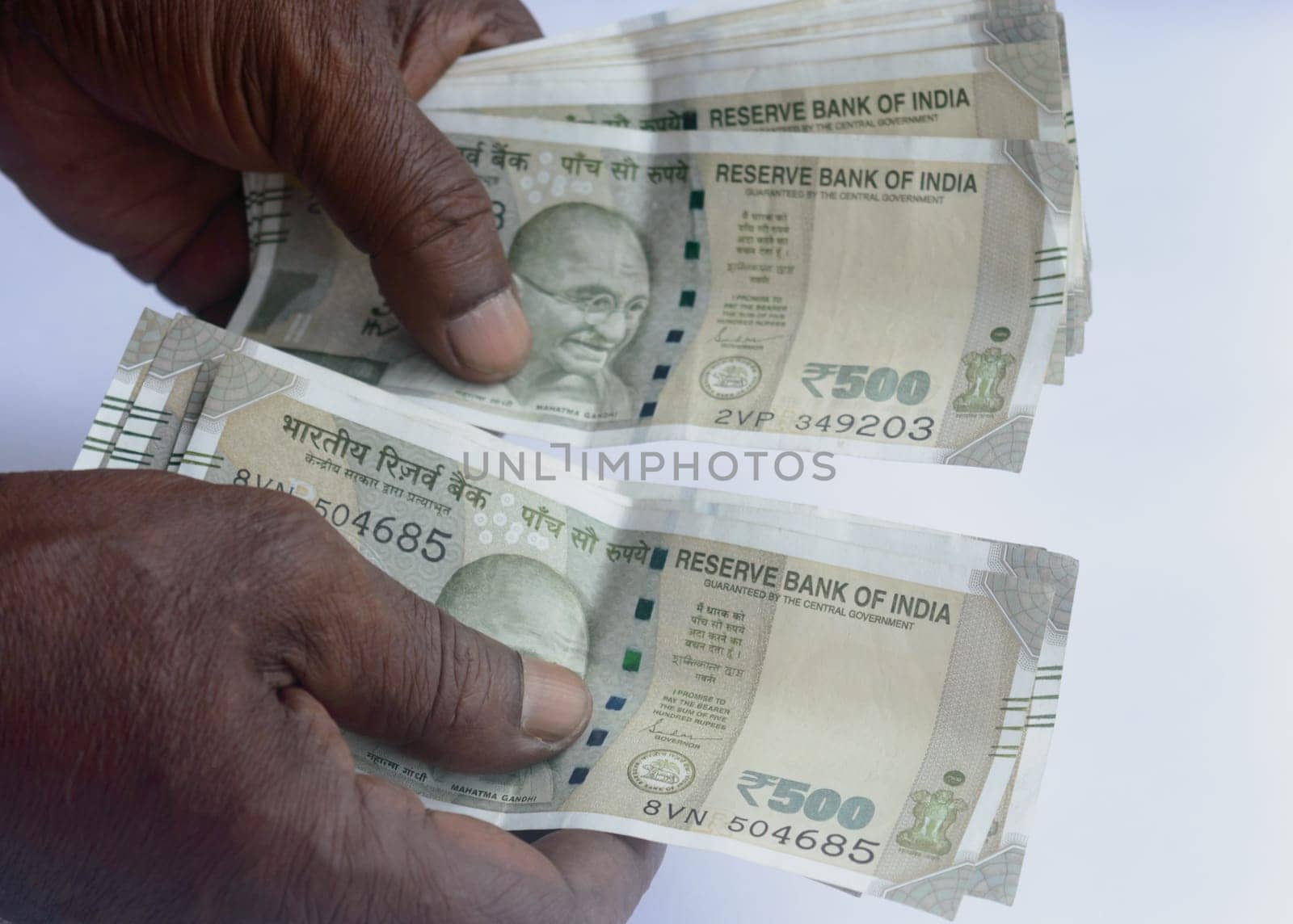 Senior aged Man hand counting Indian rupee note on table. High angle view. Close up.