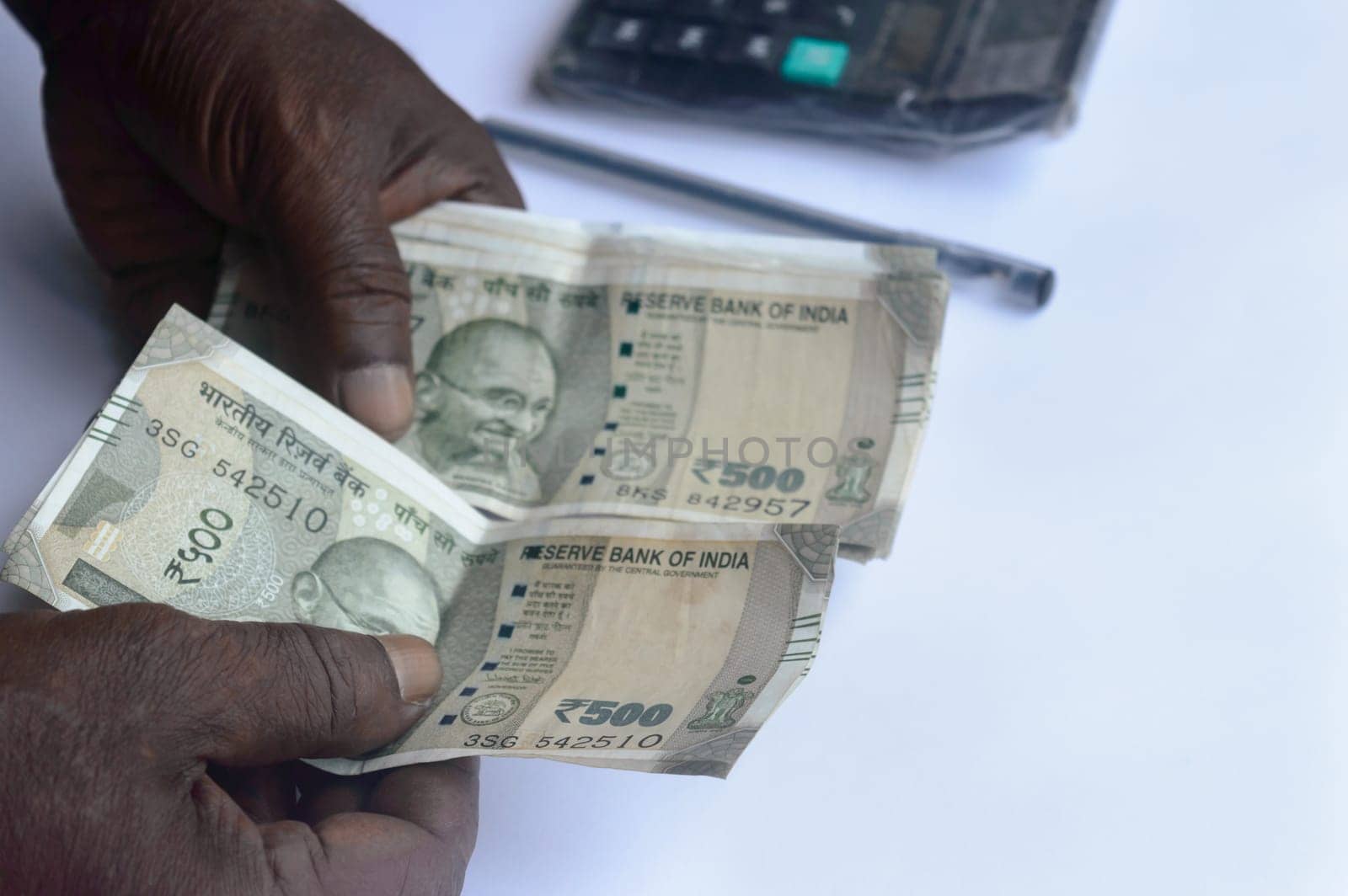 Senior aged Man hand counting Indian rupee note on table. High angle view. Close up.