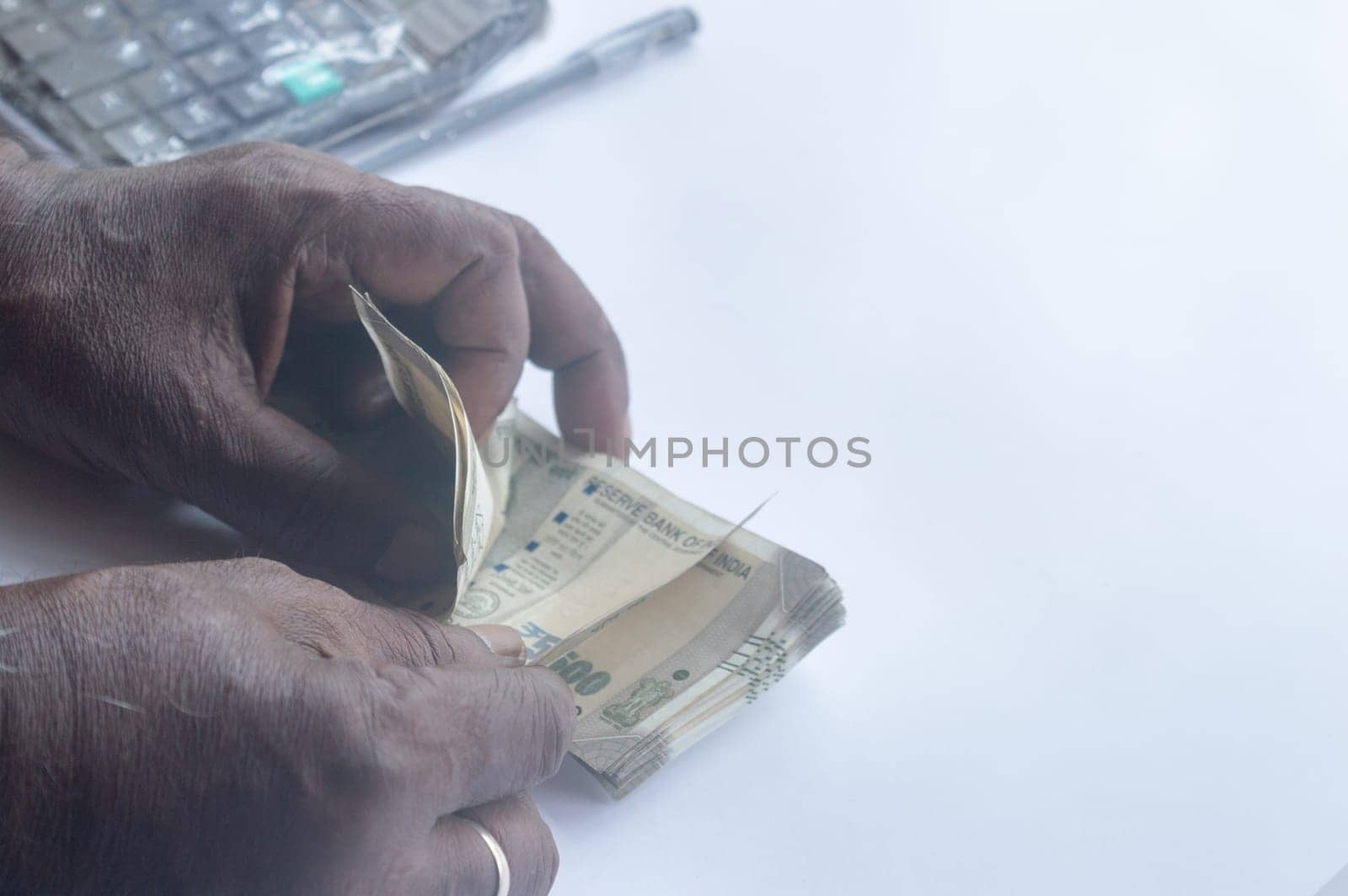 Senior aged Man hand counting Indian rupee note on table. High angle view. Close up.