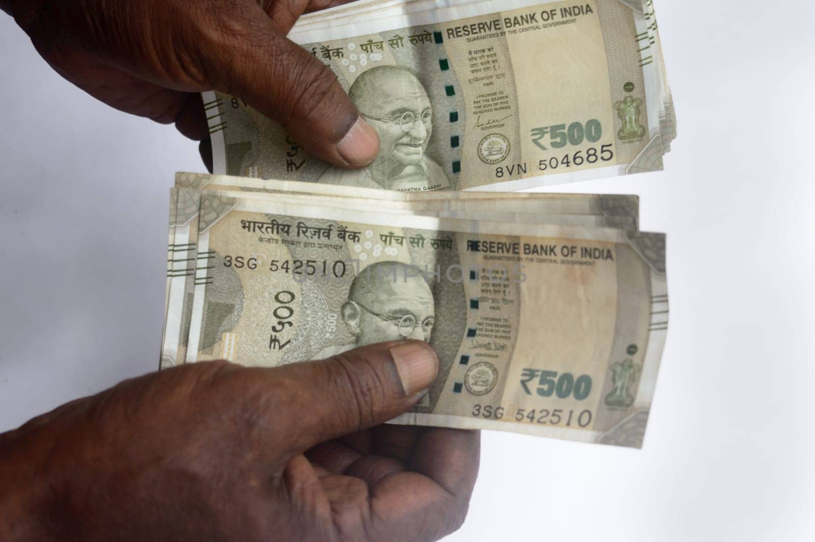 Senior aged Man hand counting Indian rupee note on table. High angle view. Close up.