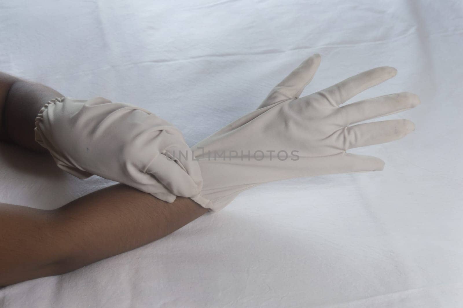 Hand Wearing Disposable Gloves against white background. High angle view. Close up. Use and protection of Hand Hygiene to reduce the risk of germs spreading due to hand contamination to environment.