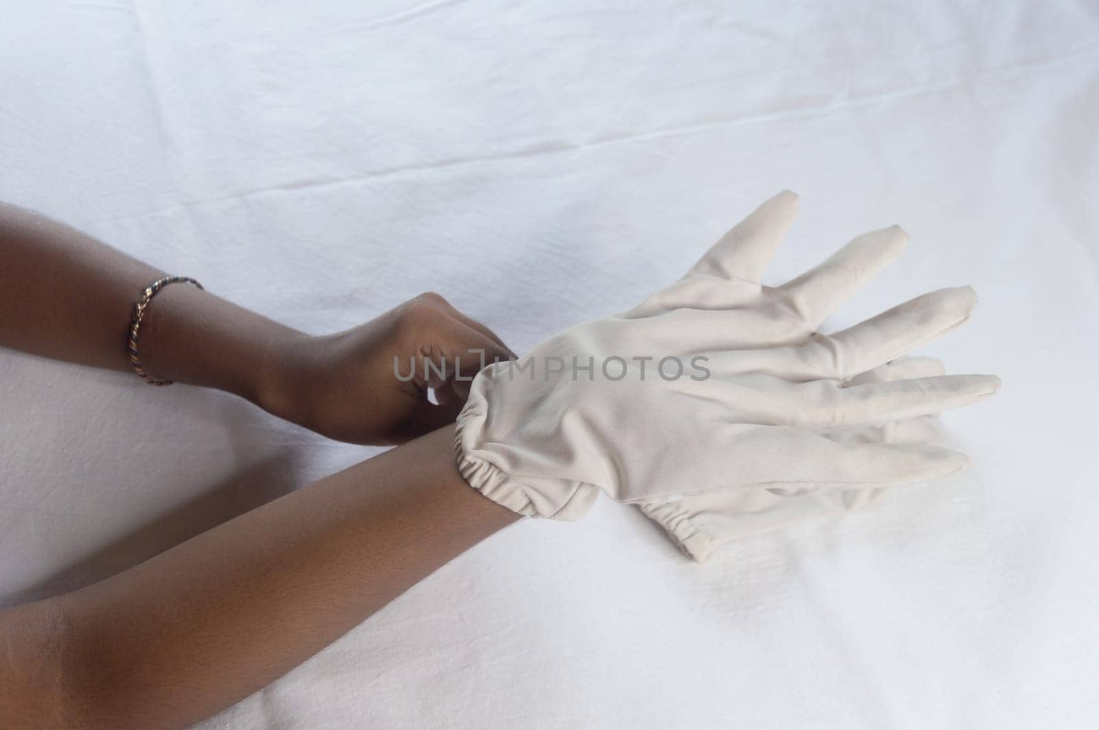 Hand Wearing Disposable Gloves against white background. High angle view. Close up. Use and protection of Hand Hygiene to reduce the risk of germs spreading due to hand contamination to environment.