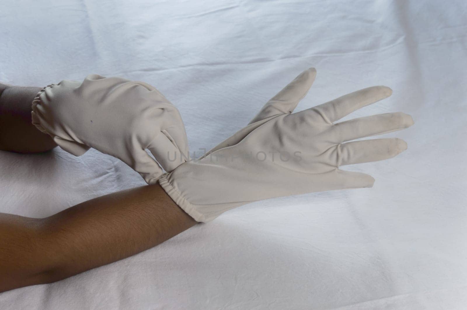 Hand Wearing Disposable Gloves against white background. High angle view. Close up. Use and protection of Hand Hygiene to reduce the risk of germs spreading due to hand contamination to environment.
