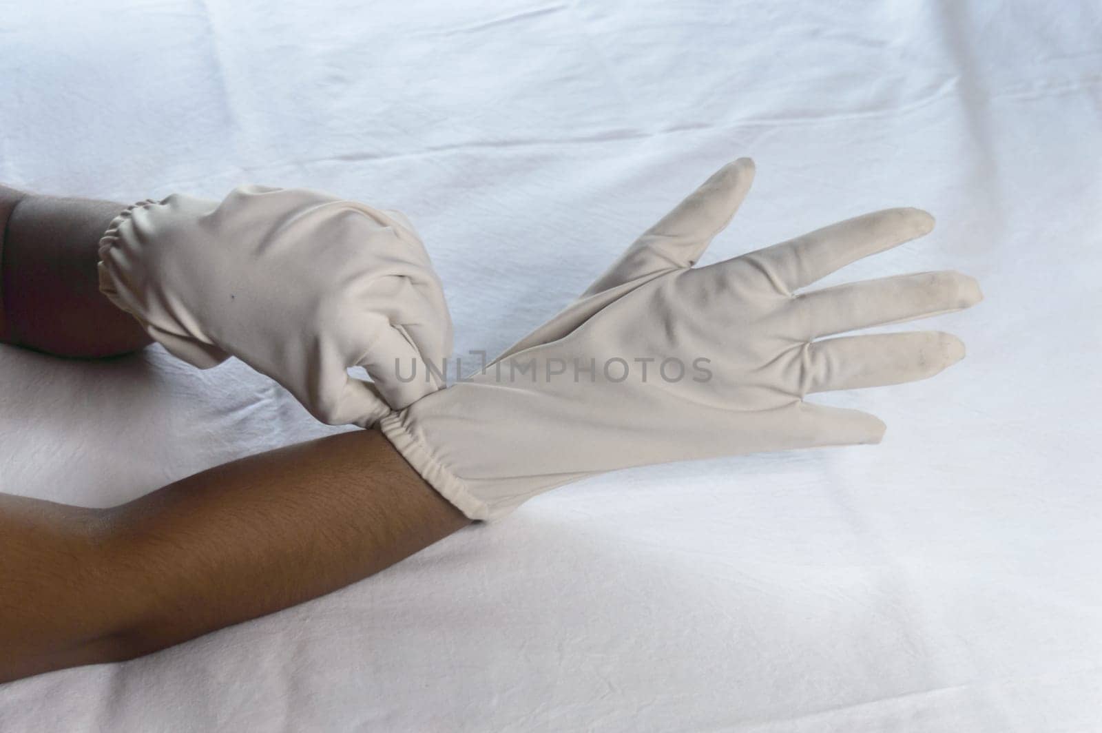 Hand Wearing Disposable Gloves against white background. High angle view. Close up. Use and protection of Hand Hygiene to reduce the risk of germs spreading due to hand contamination to environment.