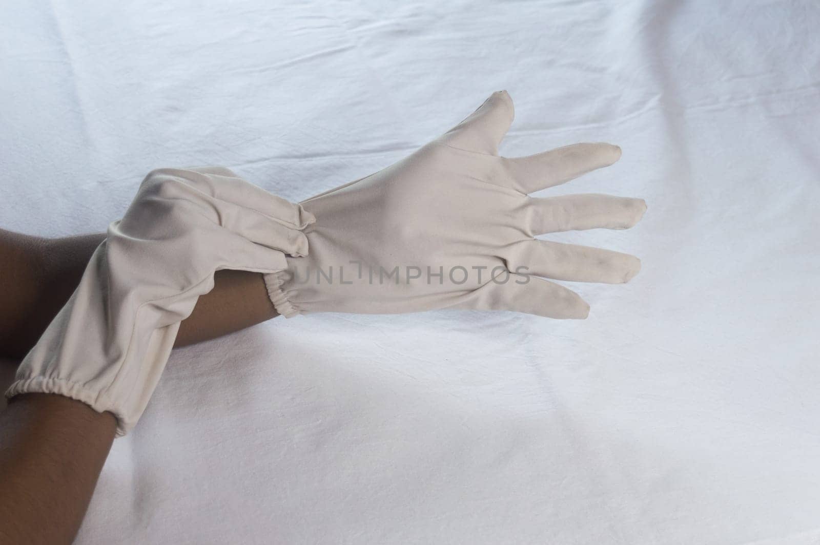 Hand Wearing Disposable Gloves against white background. High angle view. Close up. Use and protection of Hand Hygiene to reduce the risk of germs spreading due to hand contamination to environment.