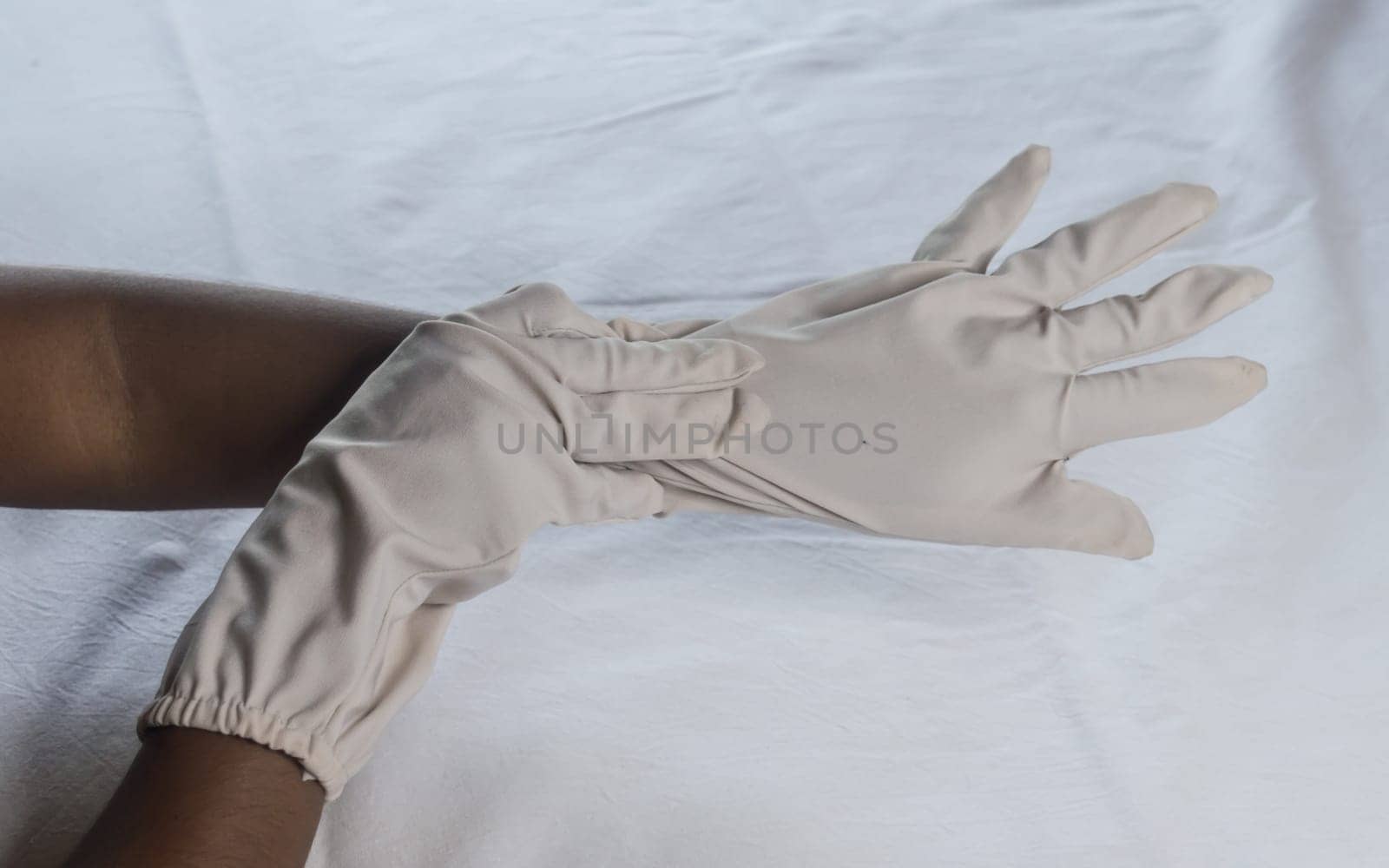 Hand Wearing Disposable Gloves against white background. High angle view. Close up. Use and protection of Hand Hygiene to reduce the risk of germs spreading due to hand contamination to environment.