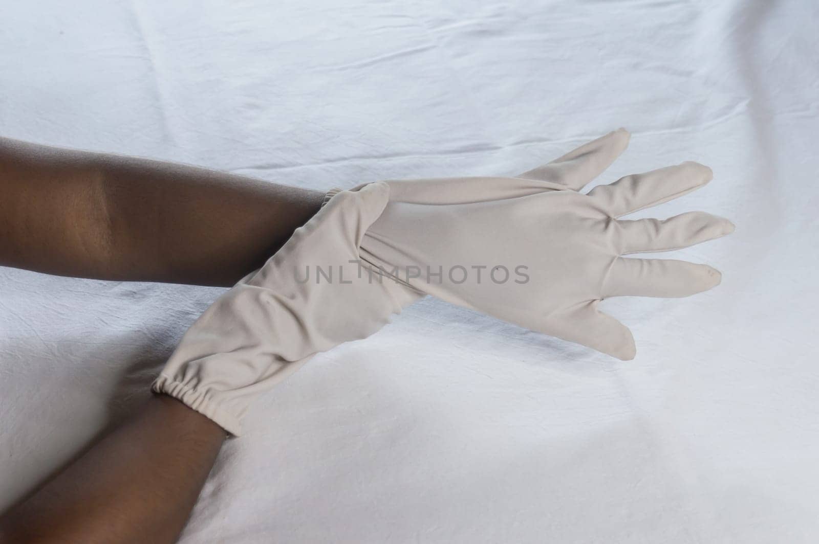 Hand Wearing Disposable Gloves against white background. High angle view. Close up. Use and protection of Hand Hygiene to reduce the risk of germs spreading due to hand contamination to environment.