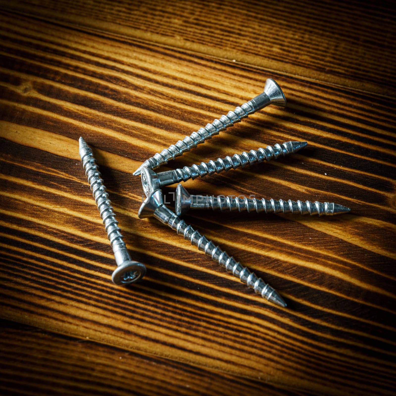 Closeup shot of a row of screws laid on a wooden table