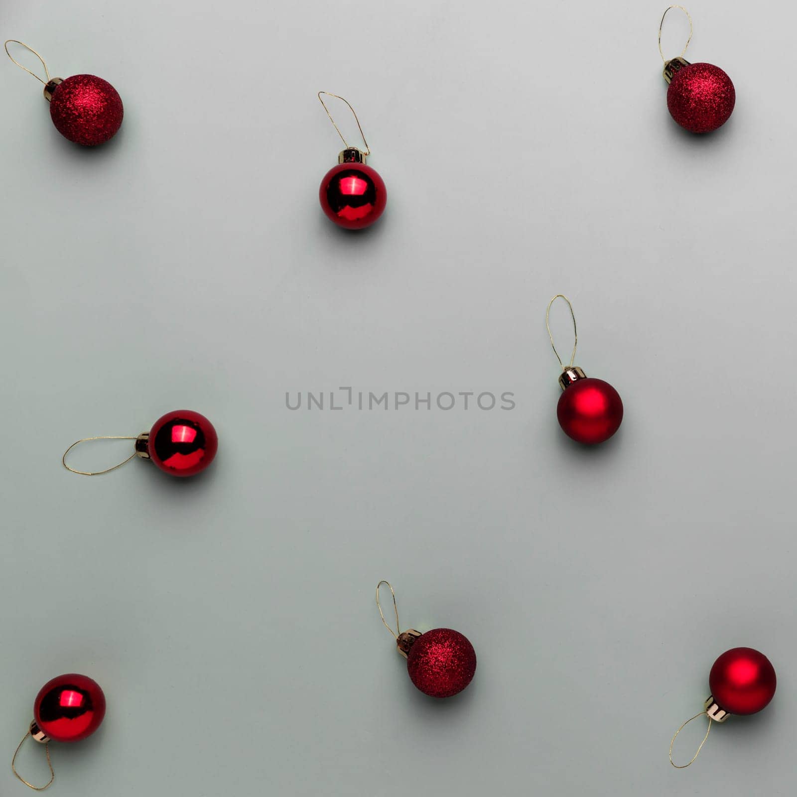 Pattern on gray background with small red Christmas balls or sphere toys for fir tree. Concept for festive minimalistic greeting card or invitation for Christmas eve celebration. High quality photo