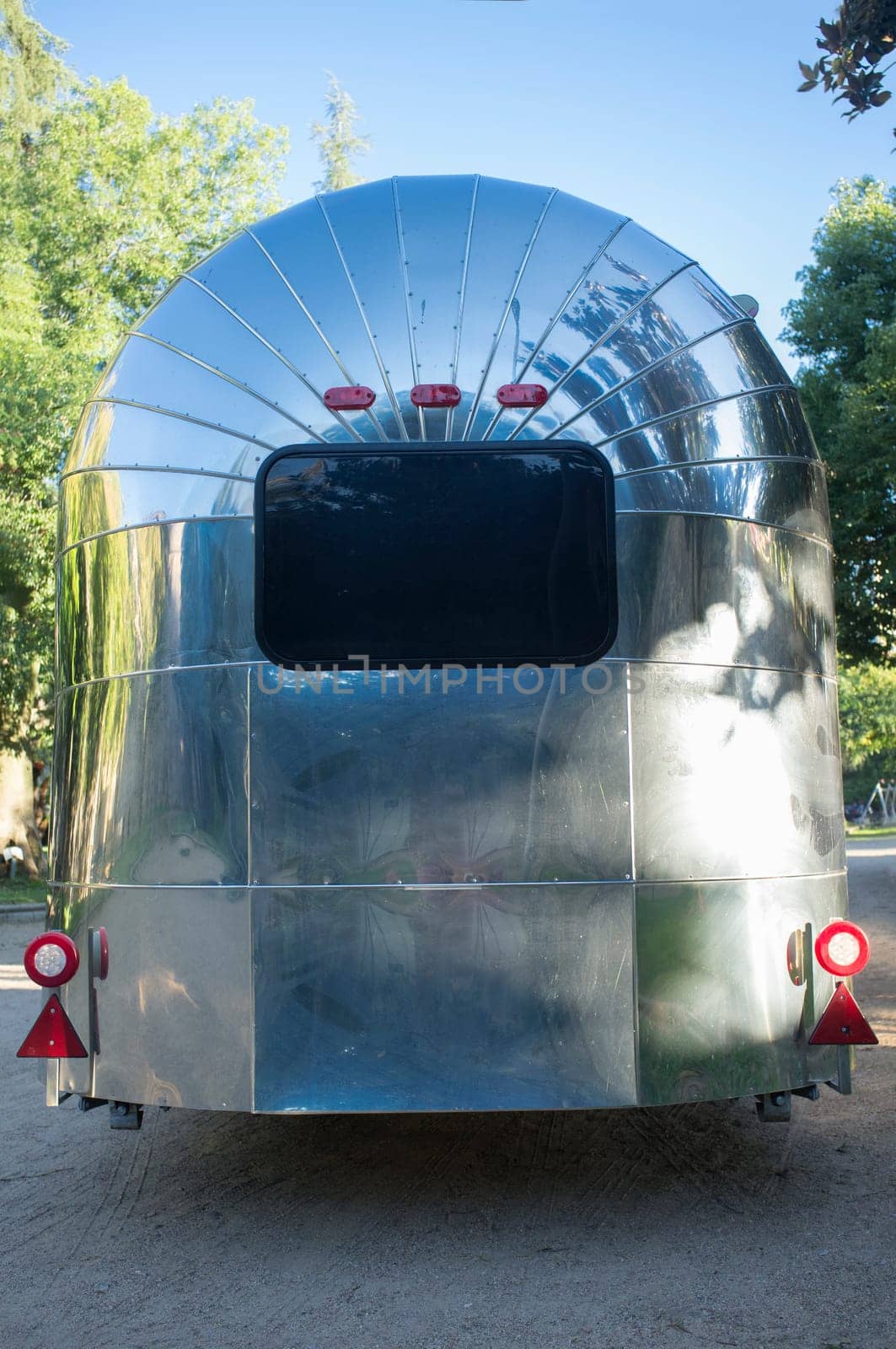 Rounded metal american caravan used as mobile catering vehicle. Rear view