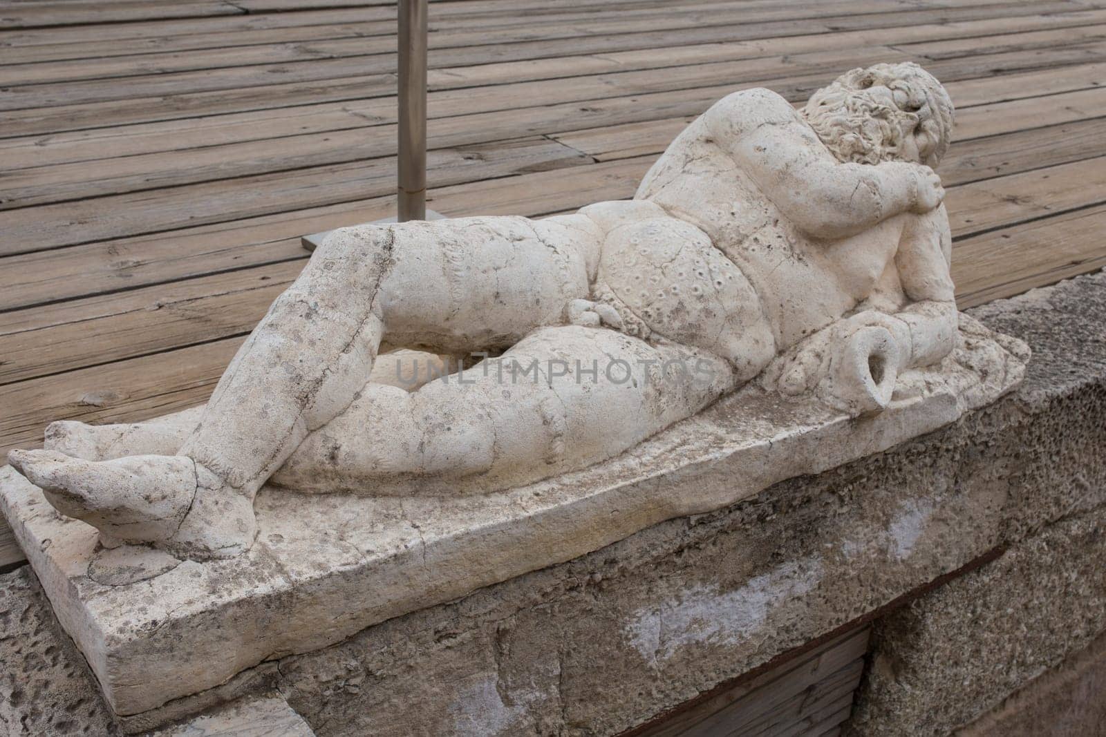 Medellin, Spain - April 28th, 2018: Old man holding an amphora. Statue-shaped fountain. Roman theatre of Medellin, Extremadura, Spain