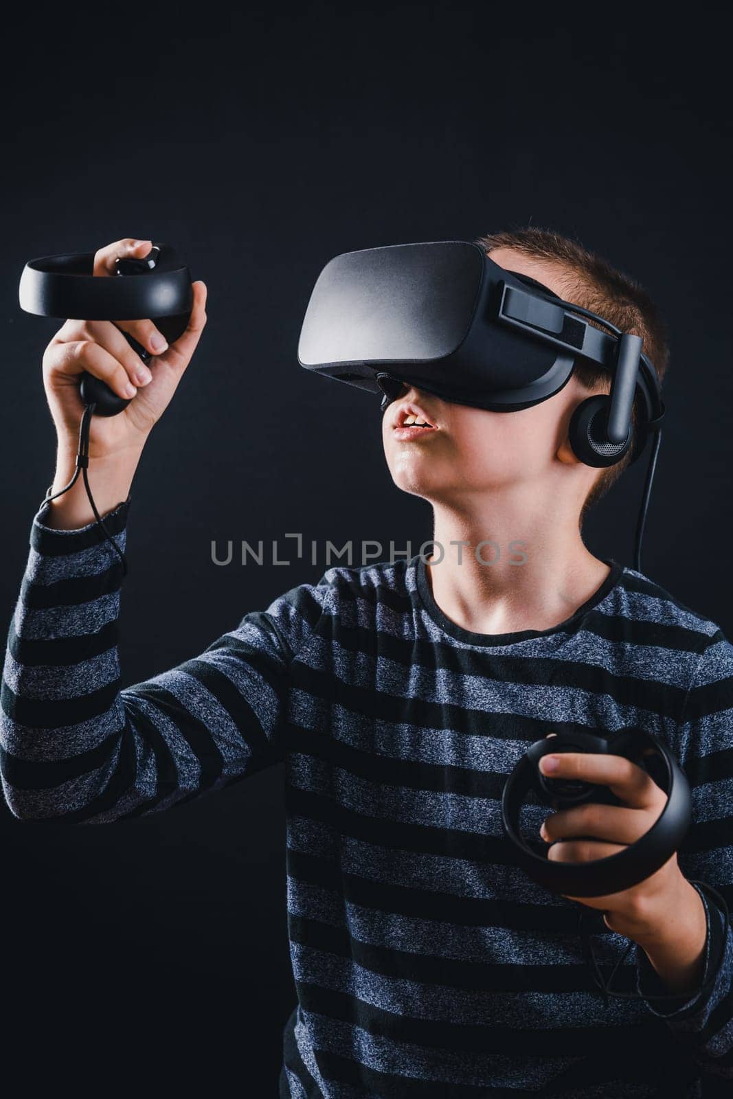 Teenager boy playing in virtual reality on black background