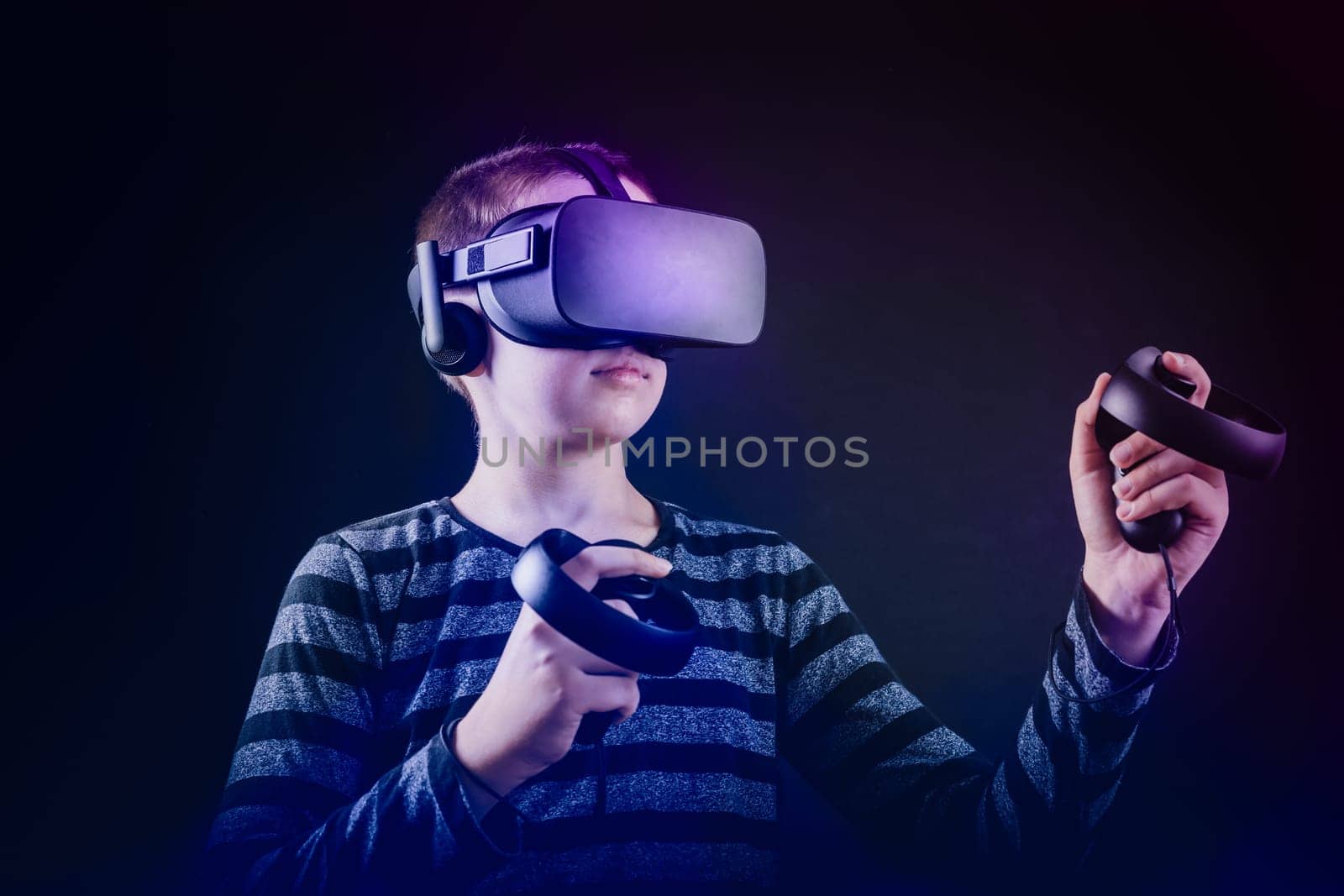 Teenager boy playing in virtual reality in neon colors, black background