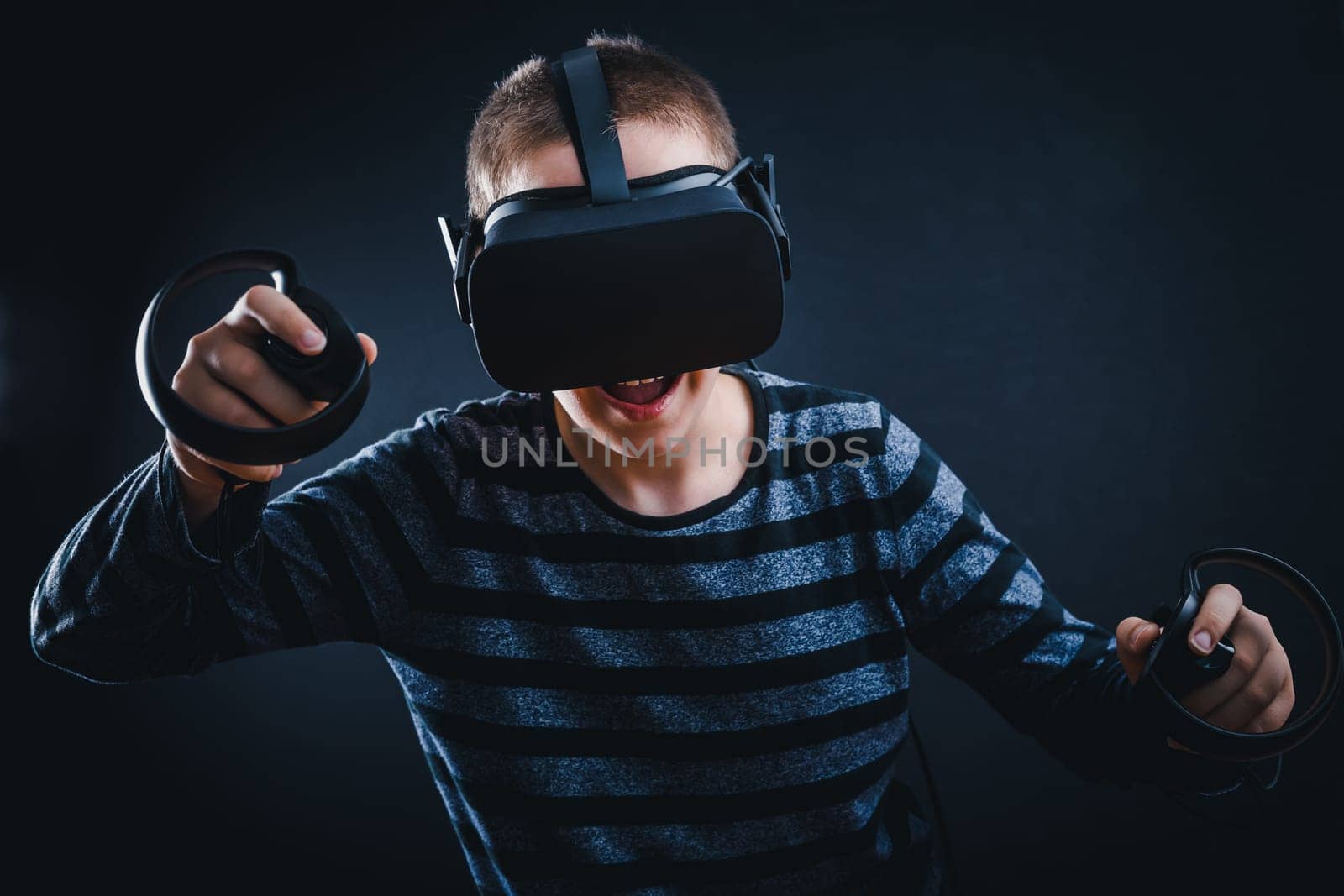 Teenager boy playing in virtual reality on black background