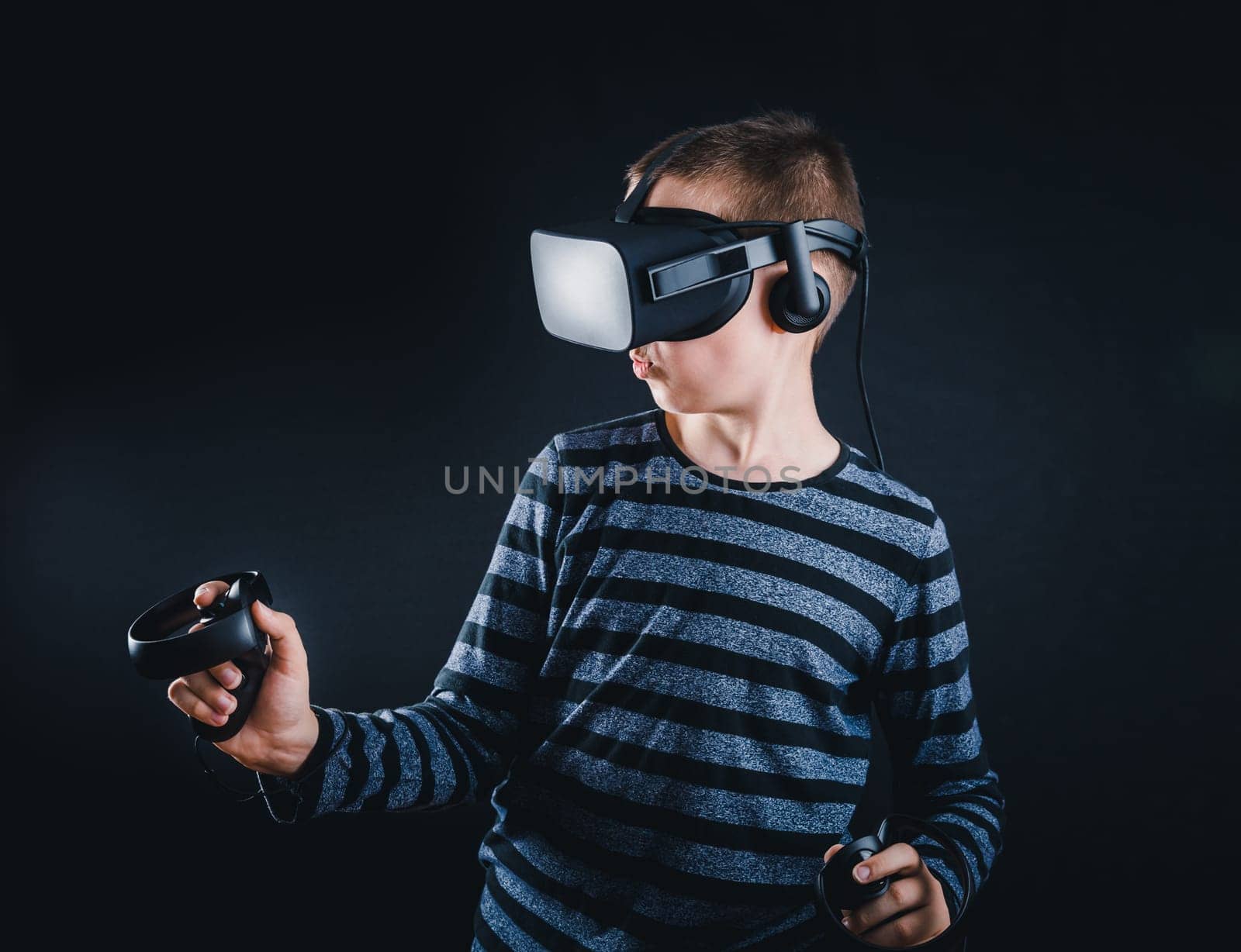 Teenager boy playing in virtual reality on black background