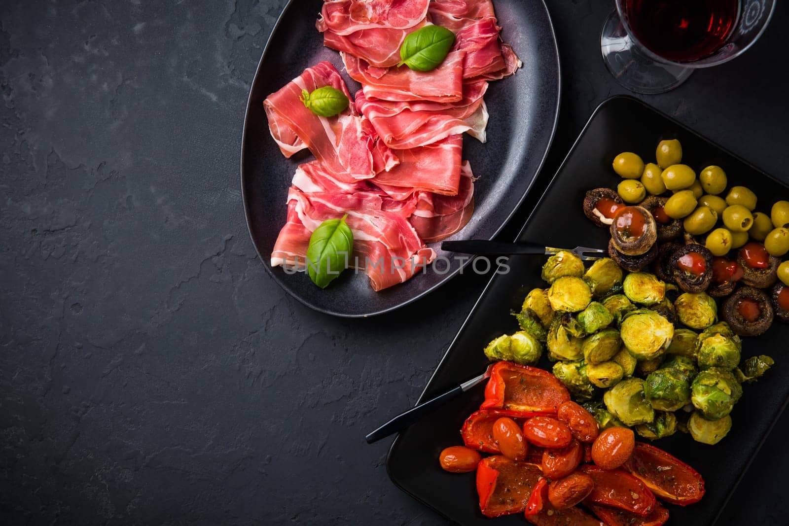 Assortment of appetizers and tapas with red wine on black background