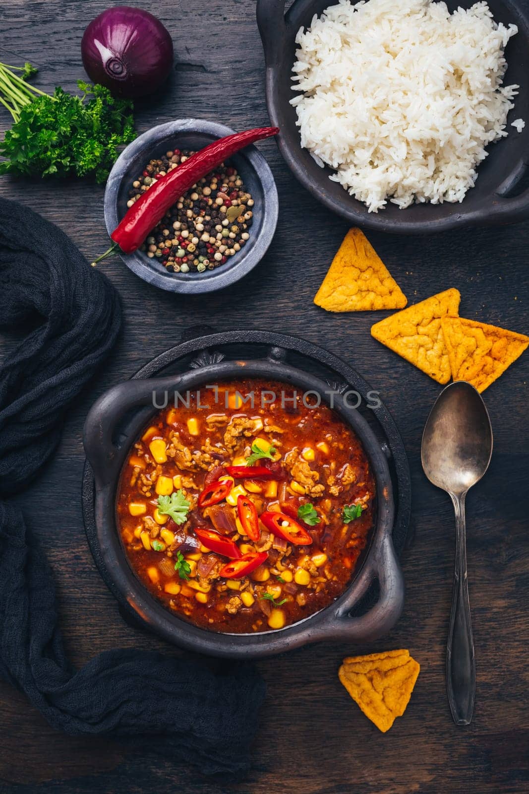 Bowl of chili con carne with rice and toppings on wooden table