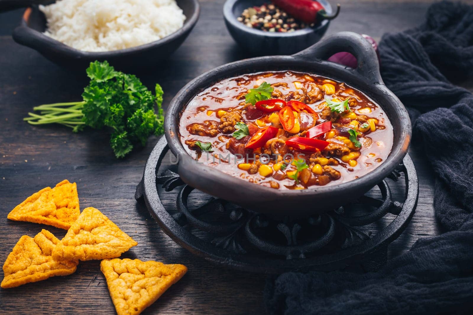 Bowl of chili con carne with rice and toppings on wooden table