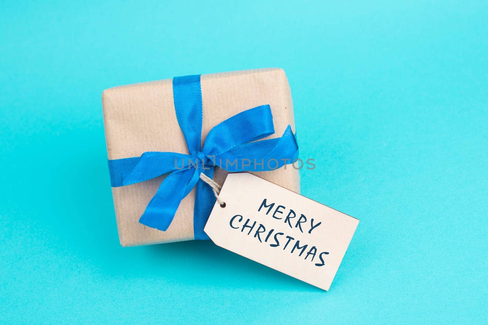 Gift box with a blue ribbon, tag with merry christmas, copy space