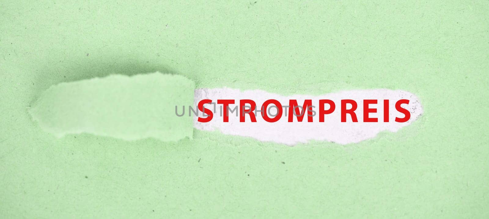 The words price for electricity are standing in german language on a torn paper in green color
