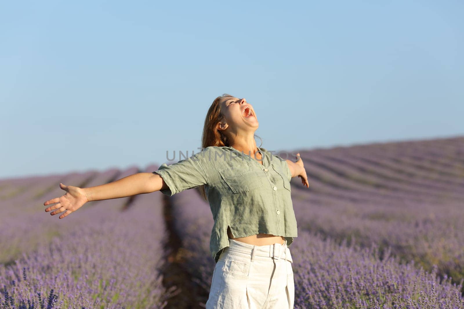 Happy woman screaming to the sky and spreading in a lavender field