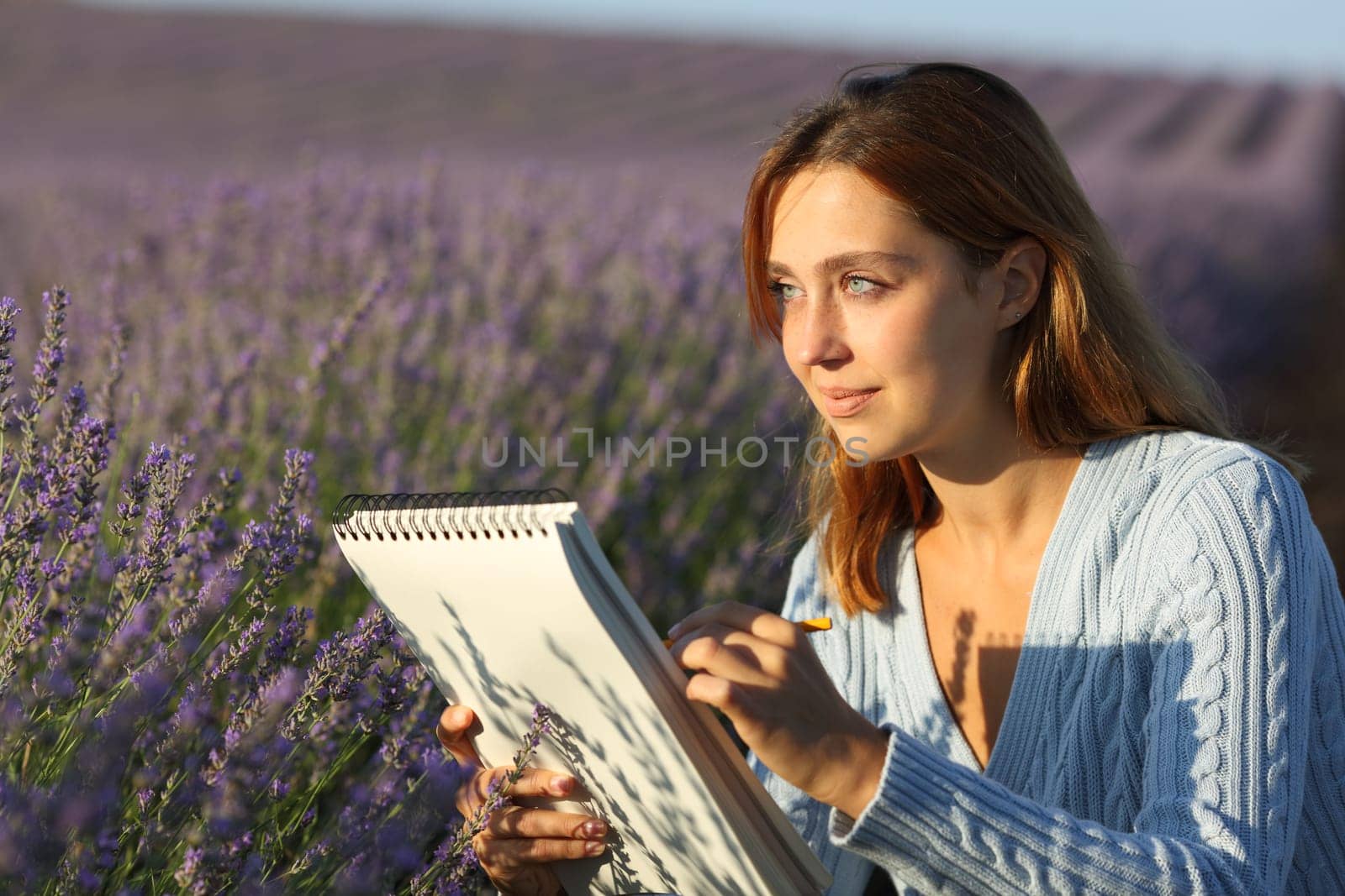 Happy woman drawing on notebook in a lavender field