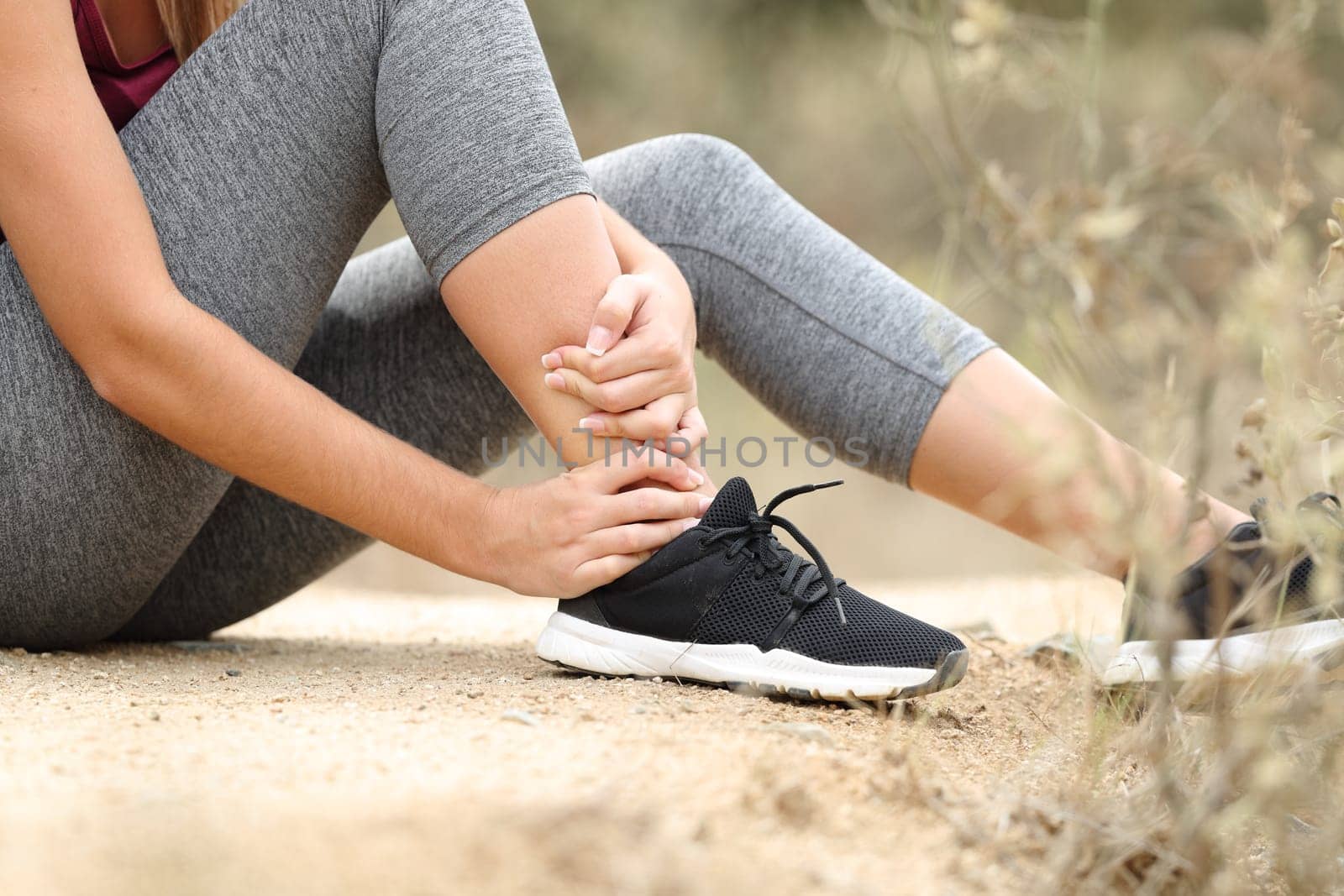 Close up of a runner suffering ankle lesion after sport in the mountain