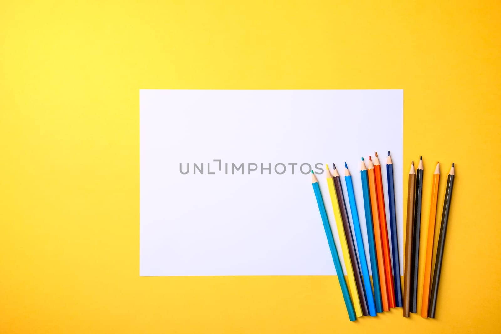 A clean white sheet and colored pencils for drawing on a yellow background with a place for copying and inscriptions. Layout, free space for the layout.