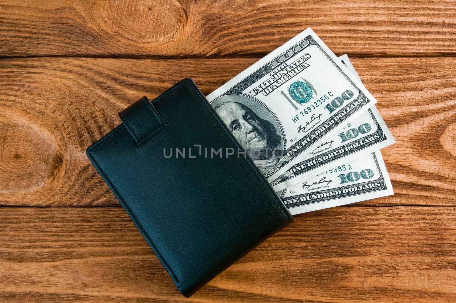 Dollars. A roll of hundred-dollar bills and scattered gold coins lying on the bills on a blue background with a side. Blue style.