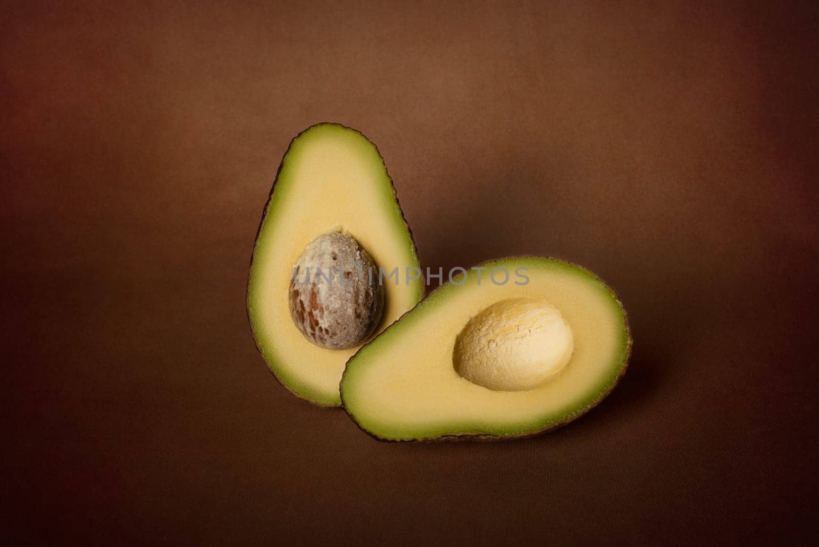 Halves of fresh avocado on a dark background. The concept of vegetarian nutrition.