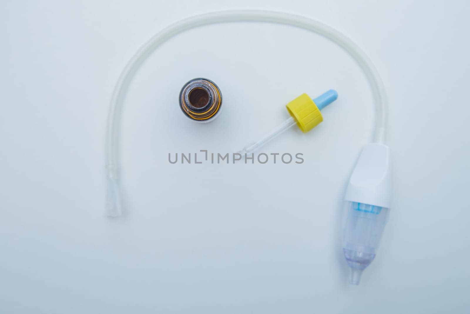 The children's aspirator lies in a semicircle on a white background, inside it are drops from a runny nose with a pipette. . High quality photo