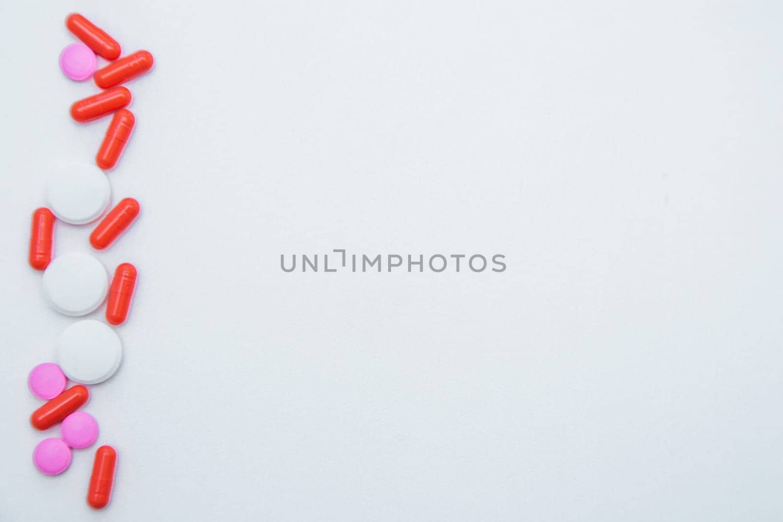 Tablets and capsules of white and pink color lie on the side on a white background. High quality photo