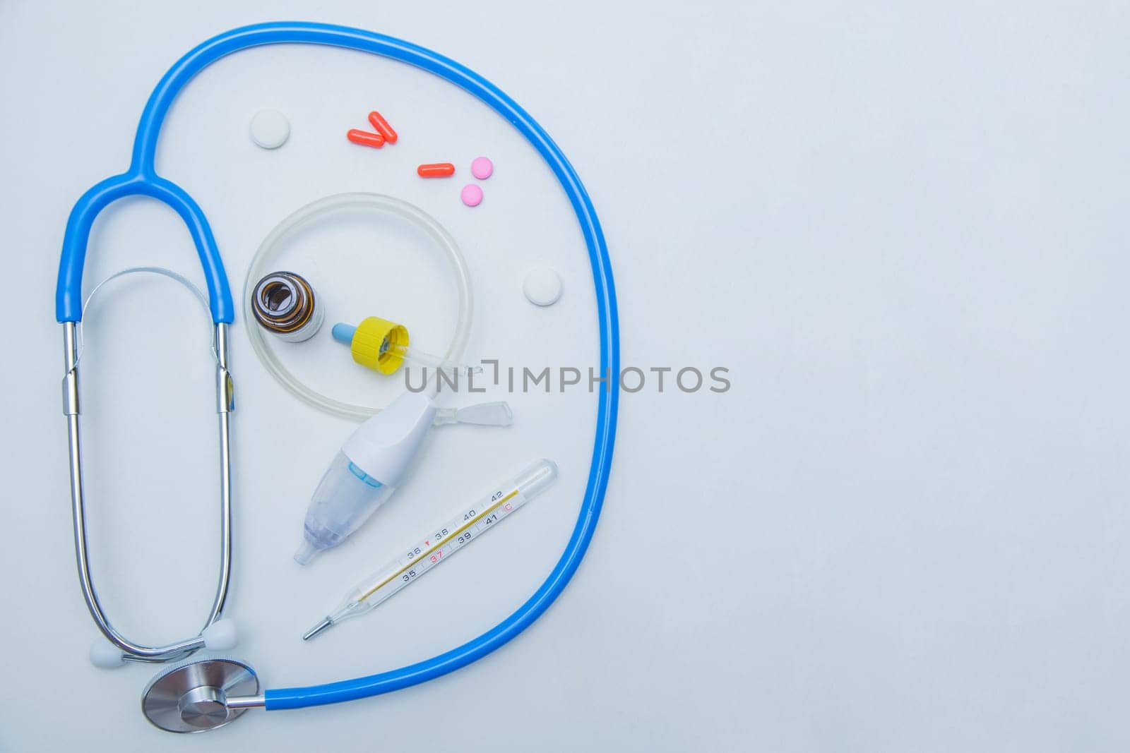 The stethoscope lies on a white background around, inside it is a baby aspirator, nose drops and pills.High quality photo