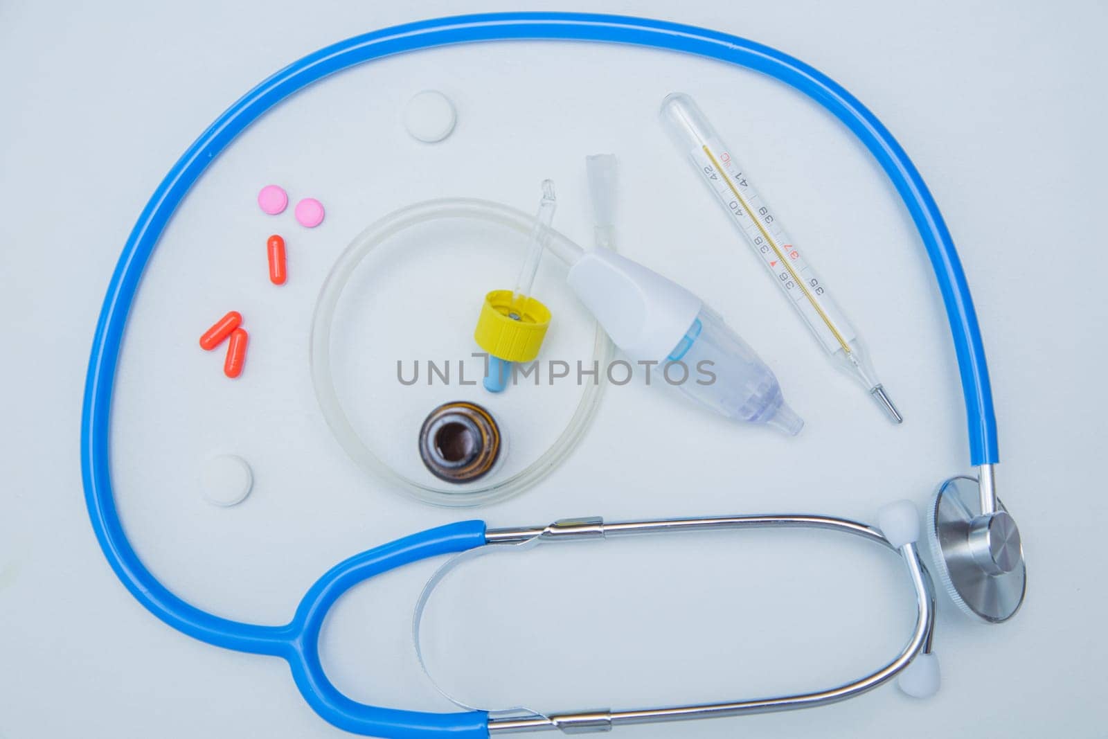 The stethoscope lies on a white background around, inside it is a baby aspirator, nose drops and pills.High quality photo