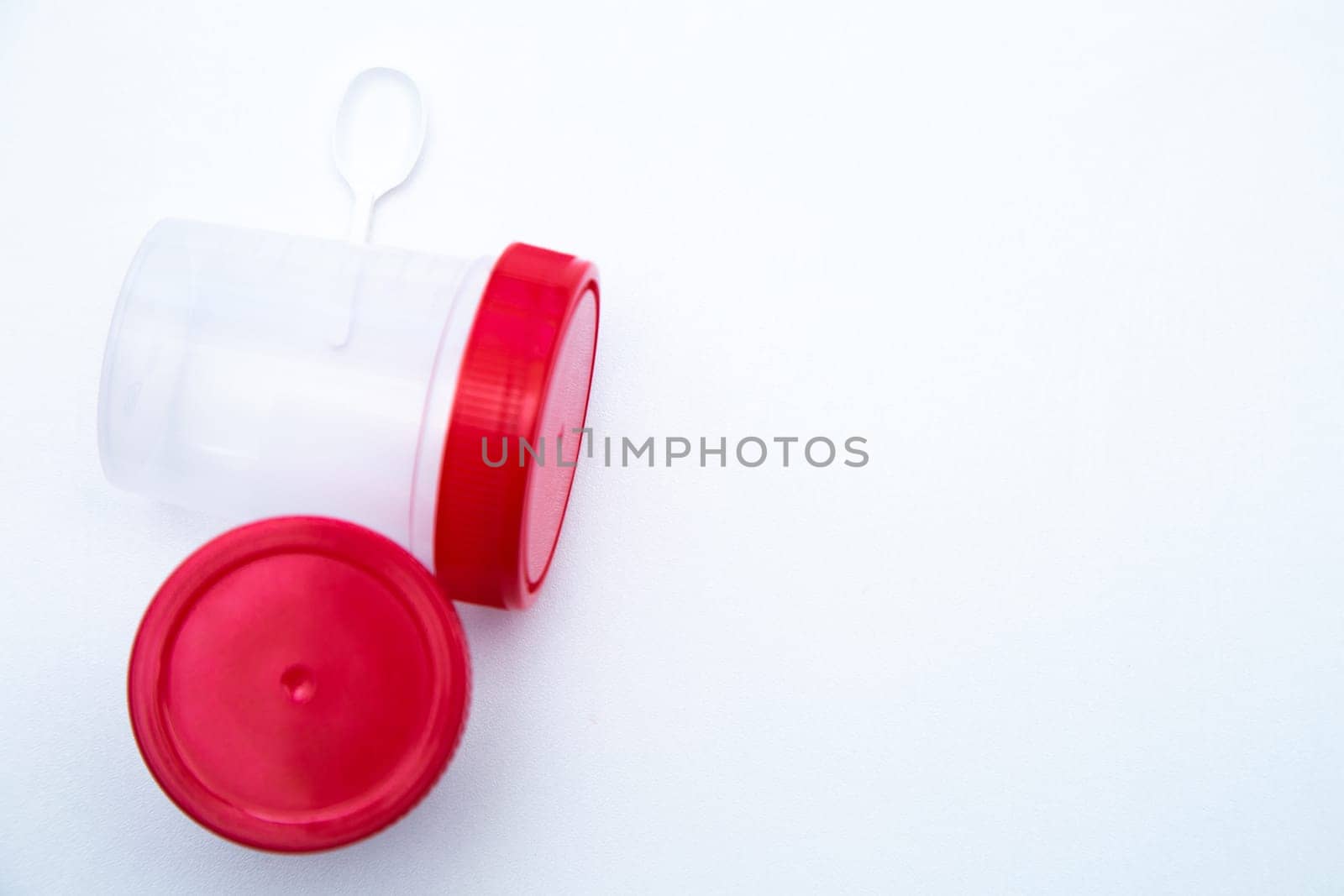 Jars for collecting tests with a red lid and a spoon on a white background. . High quality photo