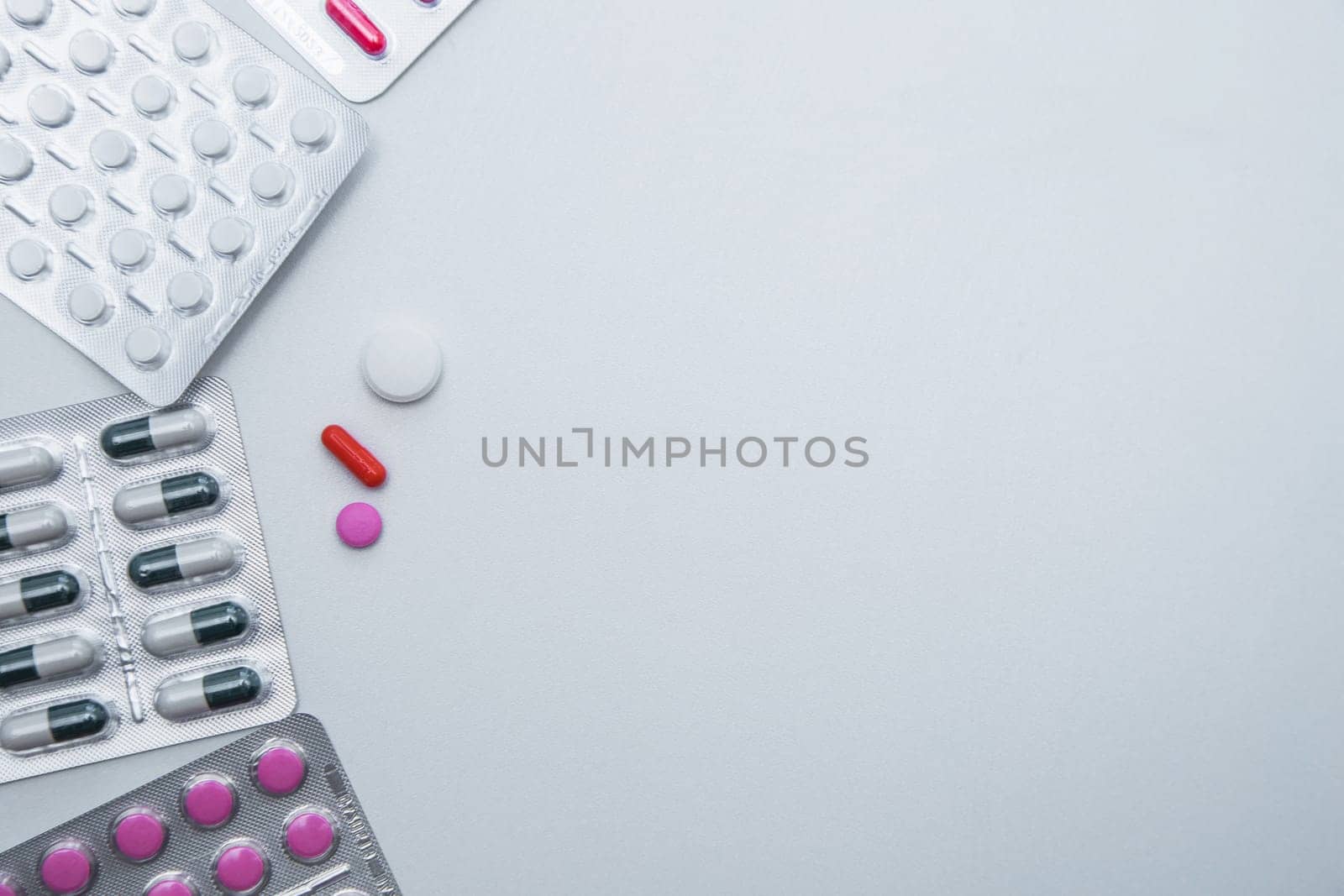 tablets and capsules in the package lie on the side with a handful of tablets on a white background with a place for text in the middle. High quality photo