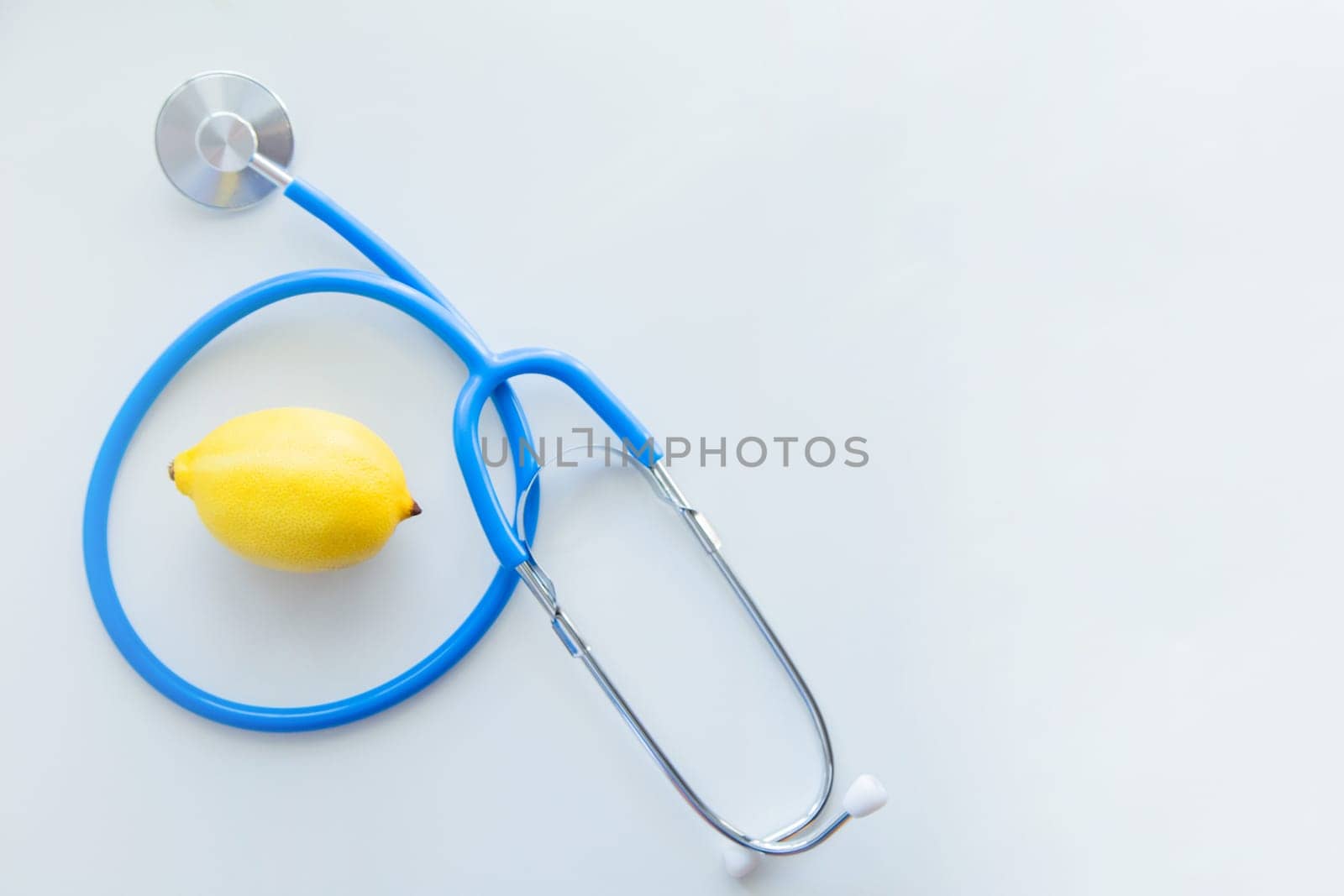 The blue stethoscope lies on a white background with a lemon in the middle. High quality photo