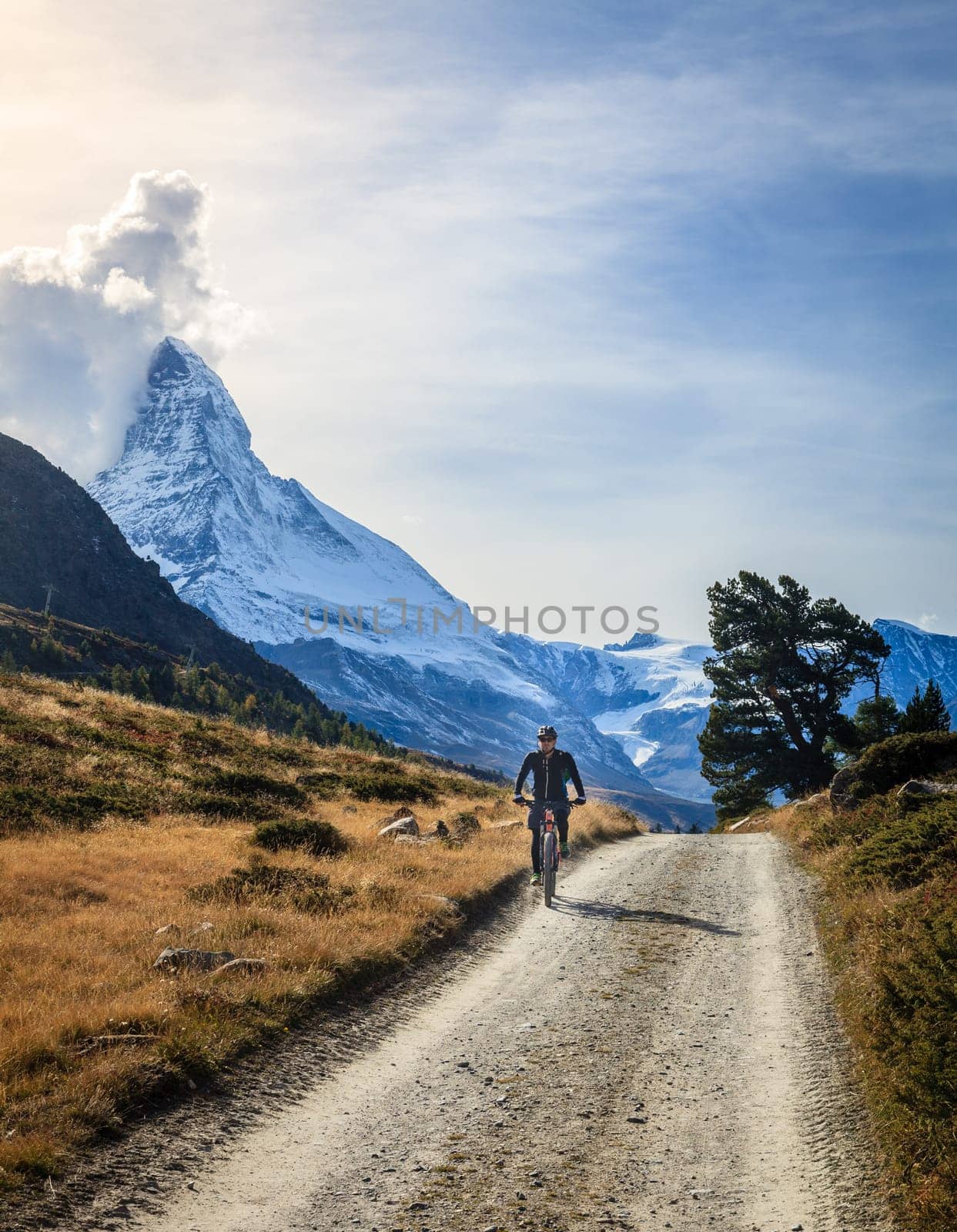 Zermatt, Switzerland, September 26, 2015: A bicyclist on a dirt road in Swiss Alps with Matterhorn in the backdrop