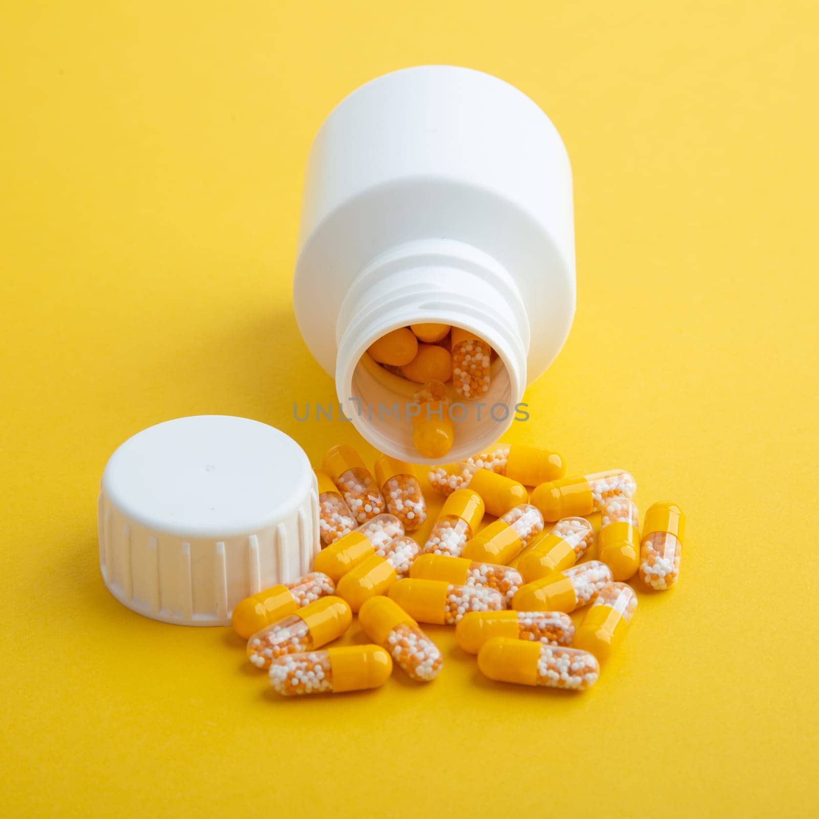 Yellow Pills with a white pill box on yellow background