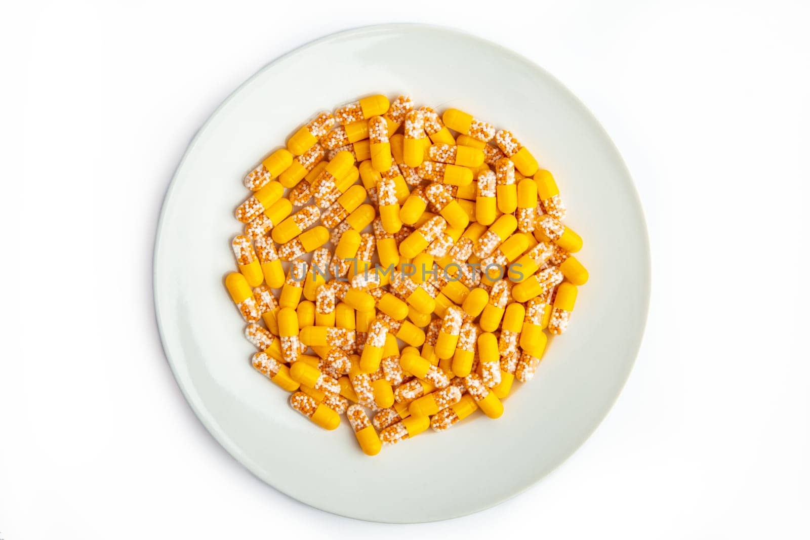 Yellow capsules on a white plate isolated on white background