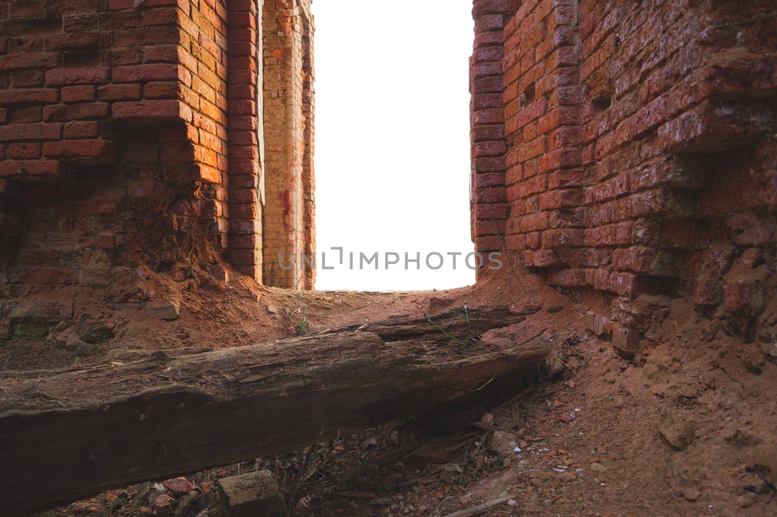 Way through red brick wall of old ruined building