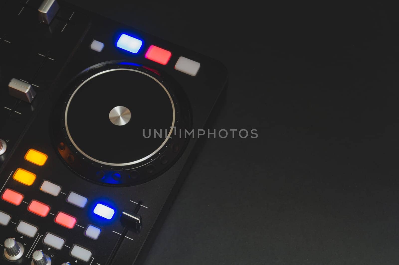Dj sound mixer controller with knobs and sliders close up. audio mixing deck with turntables at dark with illuminated controls