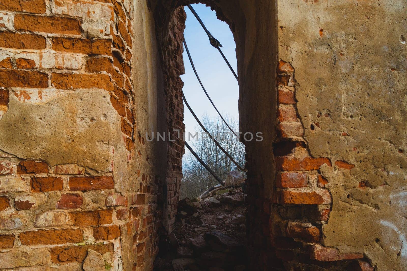 Way through red brick wall of old ruined building