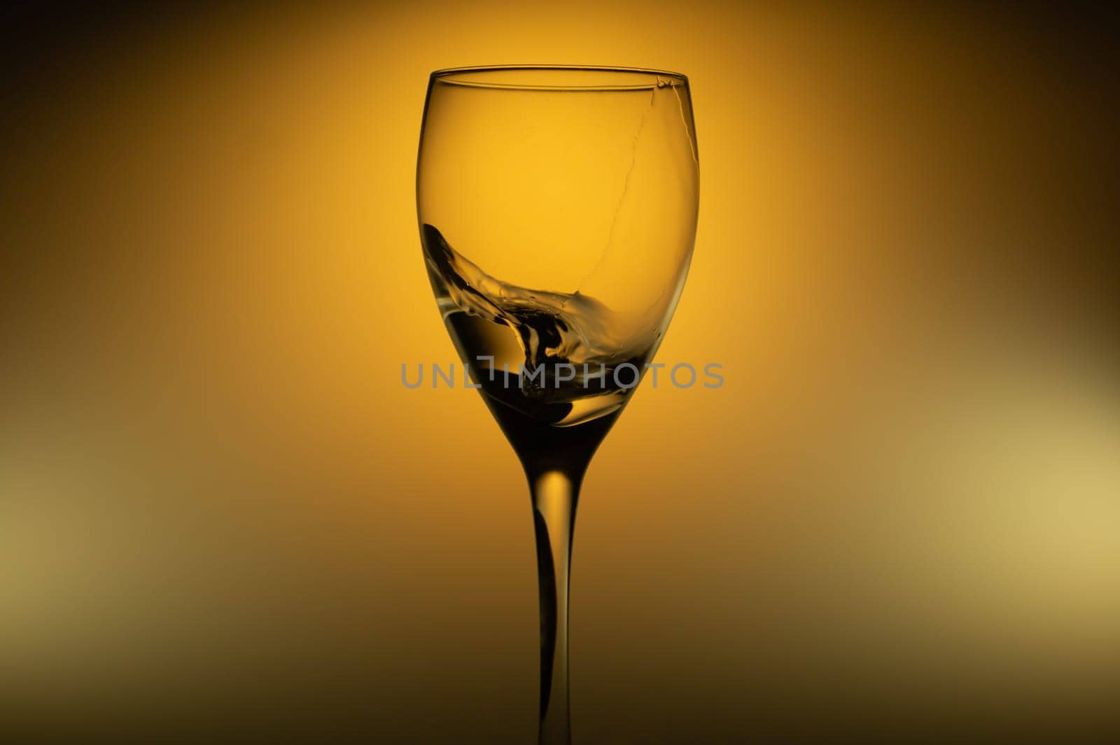 Water splash in glass on glowing background. splashing water in wine glass. transparent cocktail