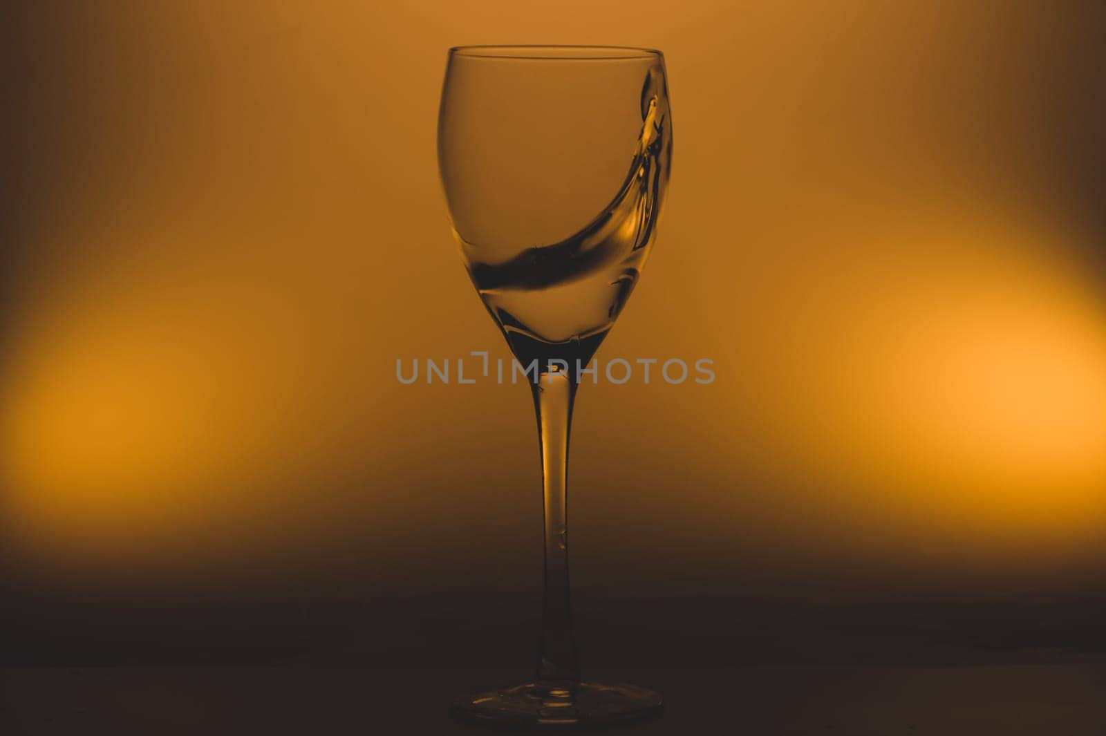 Water splash in glass on glowing background. splashing water in wine glass. transparent cocktail