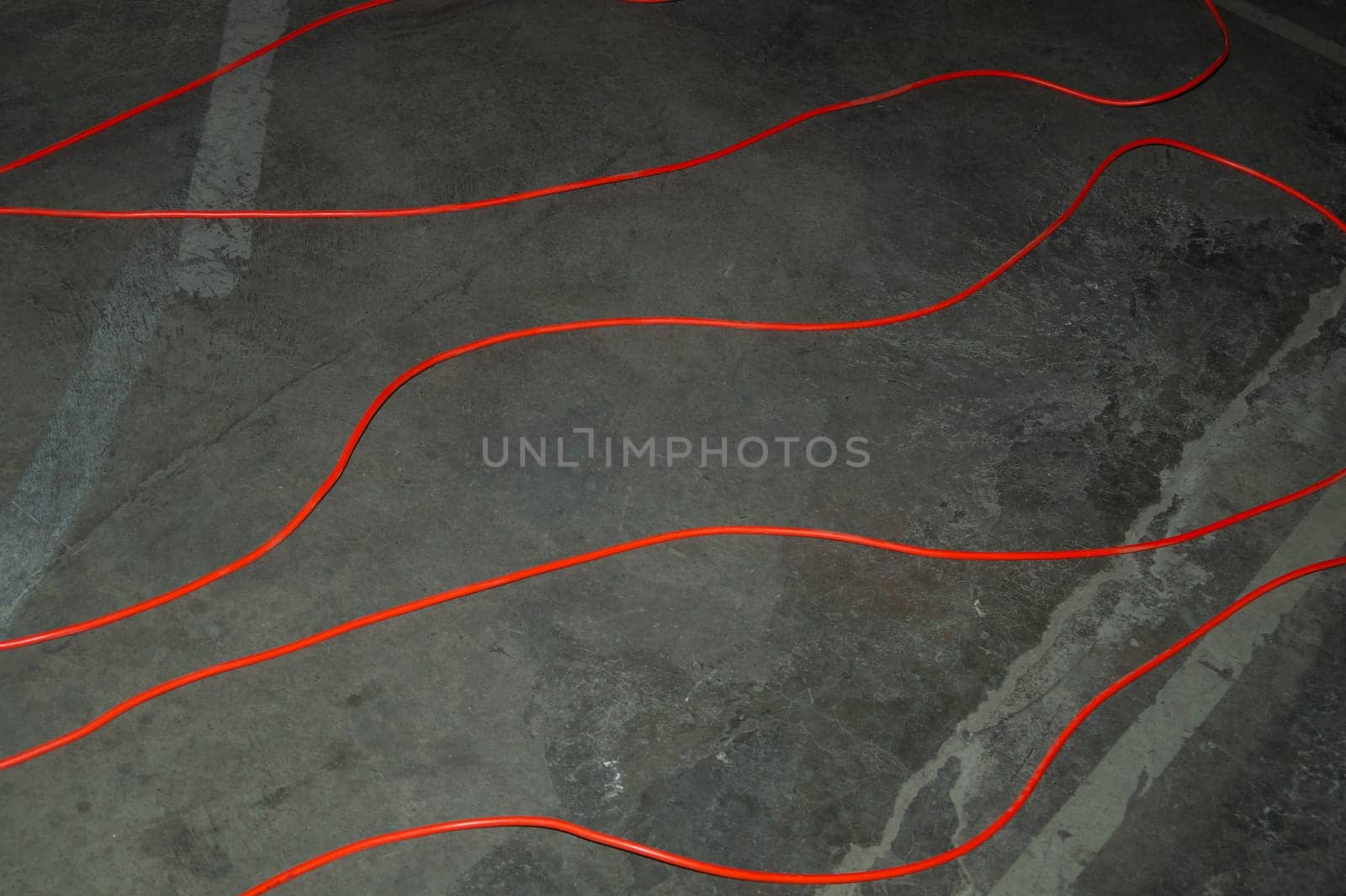 Red electric power cable. red wire lies on the ground. mess on cement floor. industrial background